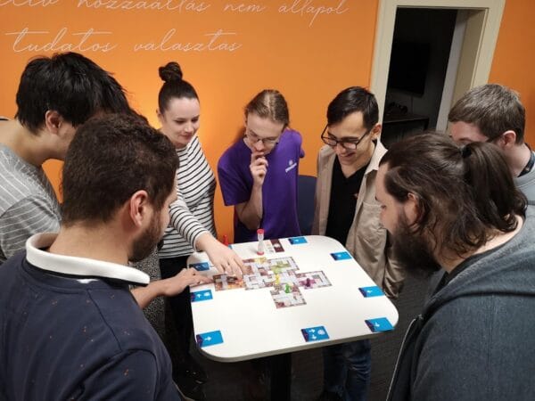 8 ember ül egy asztal körül és játszanak.