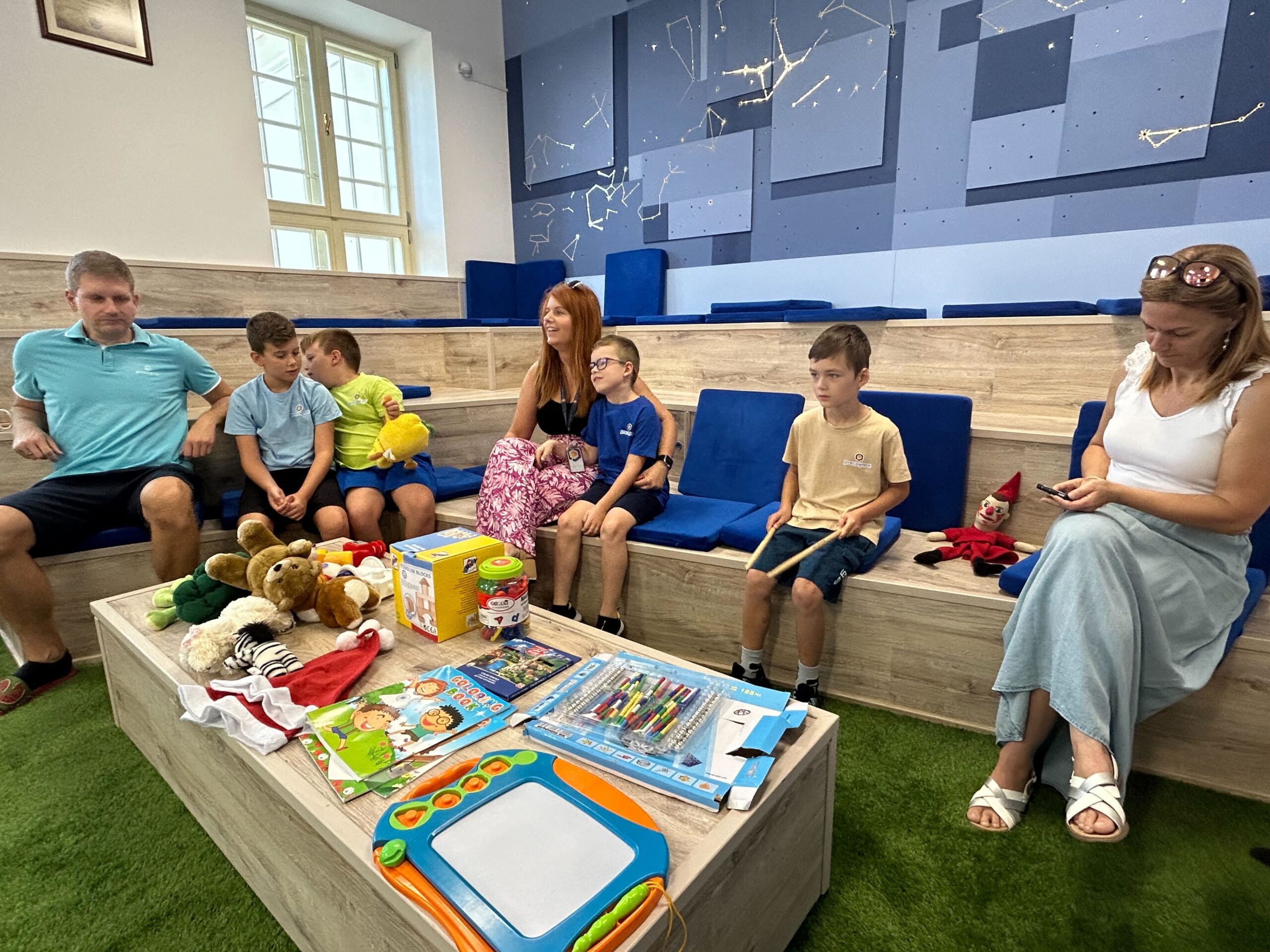 3 families are sitting on a room decorated with stars. There are children gadgets in front of them.