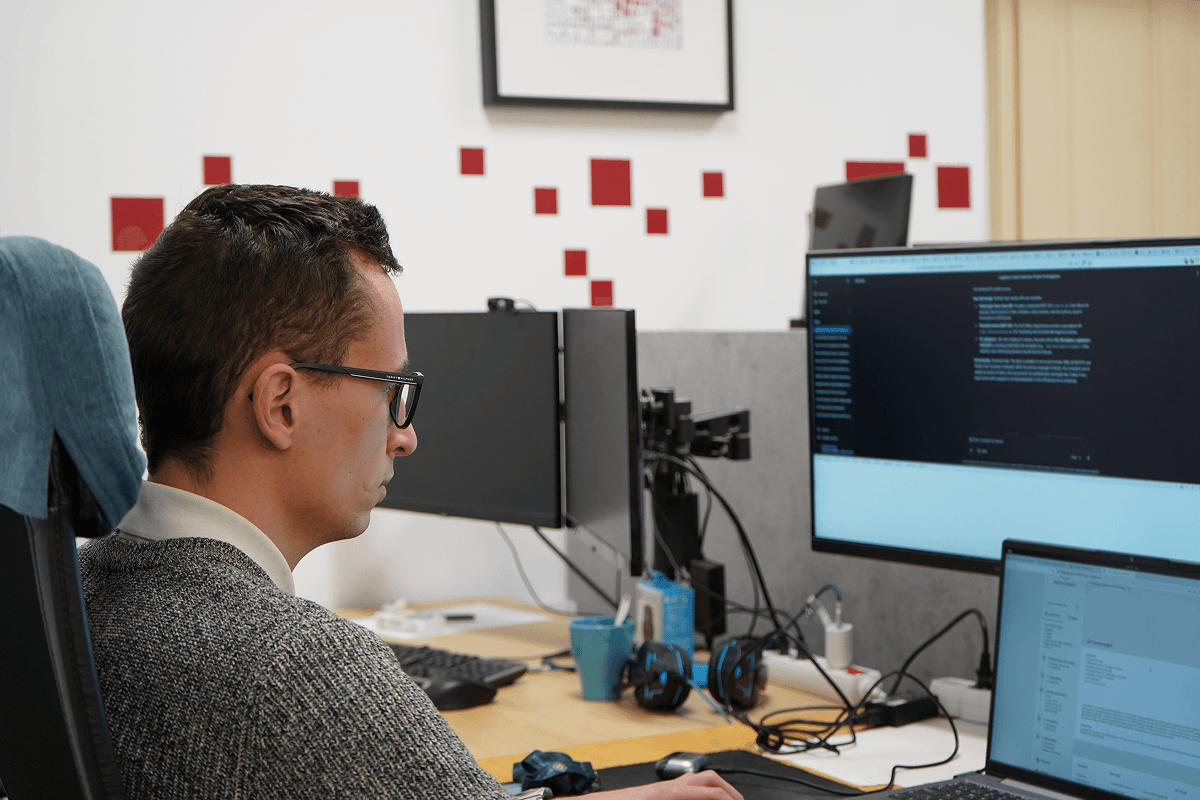 A Precognox colleague working in the office in front of monitors.